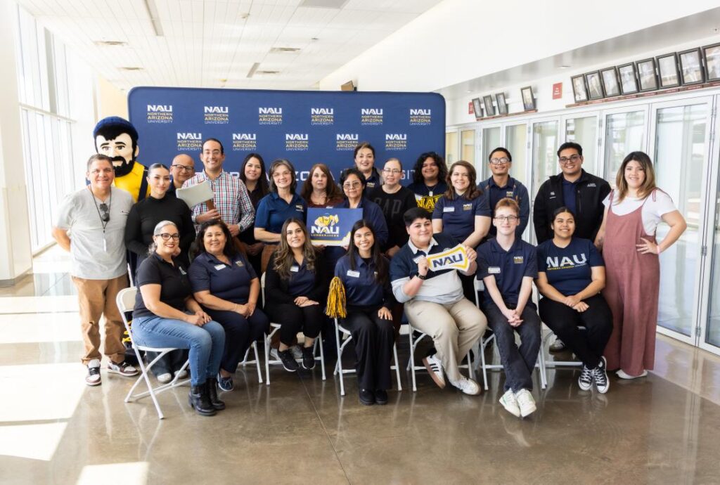 Group of people from AZ Ahead smiles for group photo in front of NAU step and repeat.
